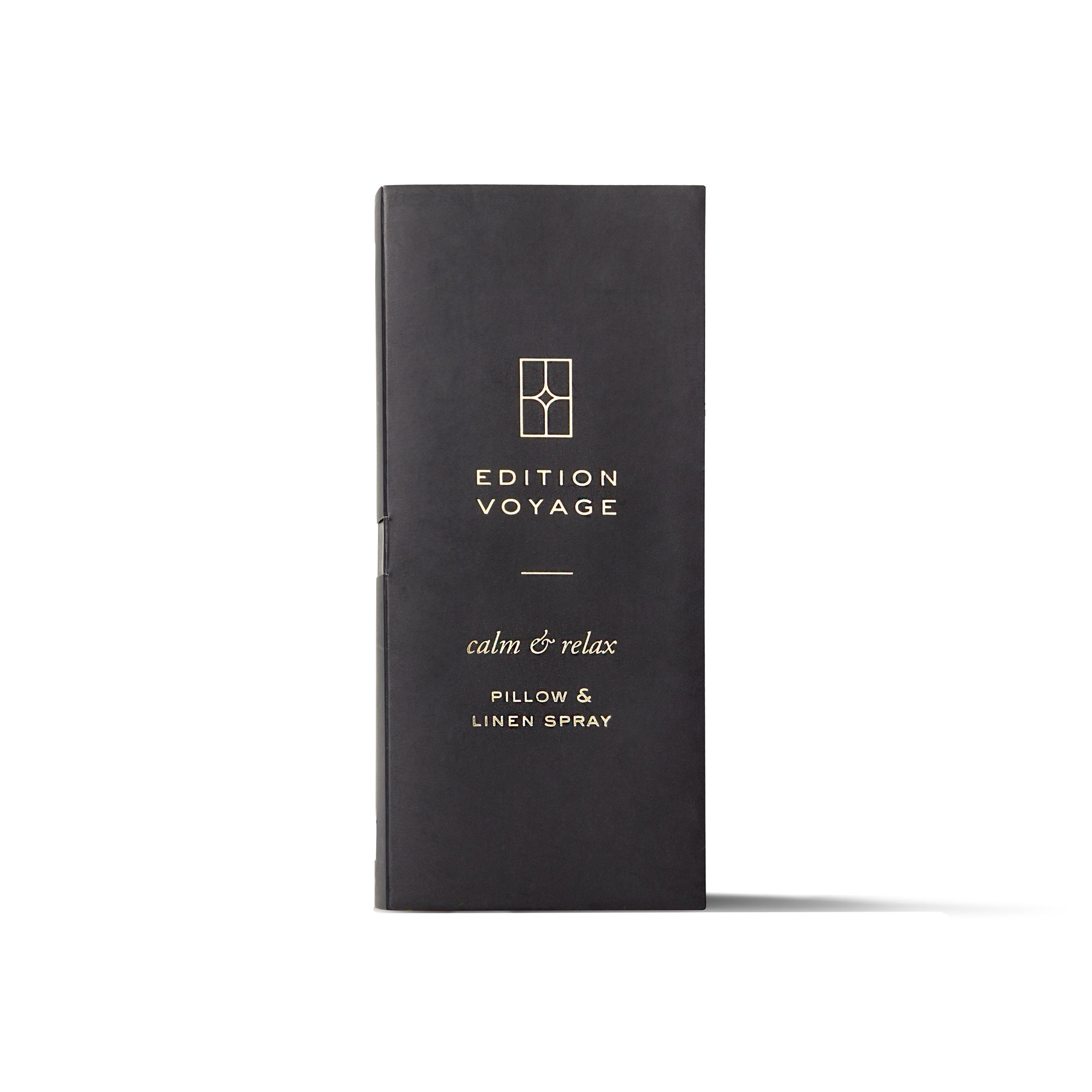 An Edition Voyage Pillow & Linen Spray bottle standing next to its black box.