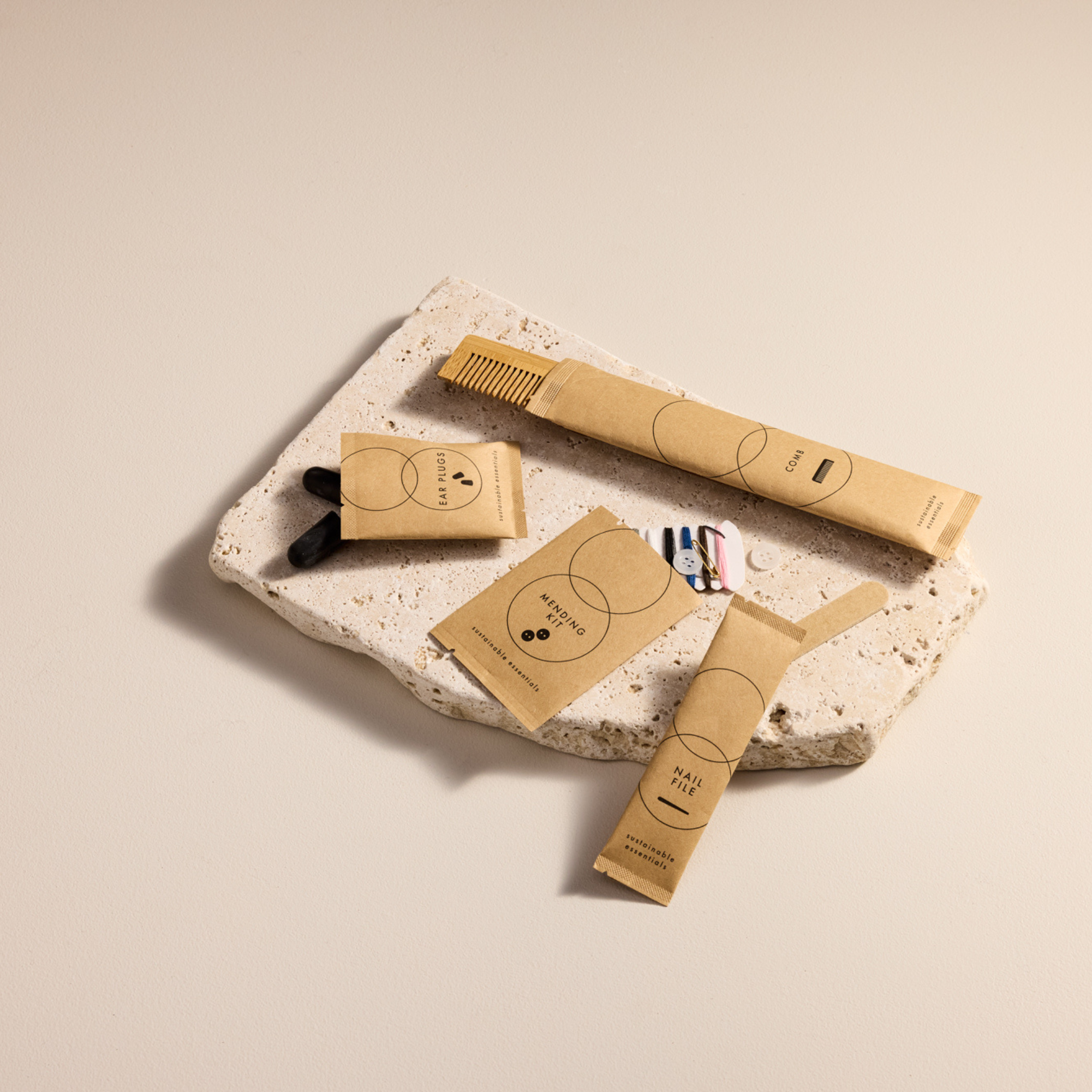 A flat lay of brown paper hotel vanity kits and a wooden comb arranged on a travertine stone block.