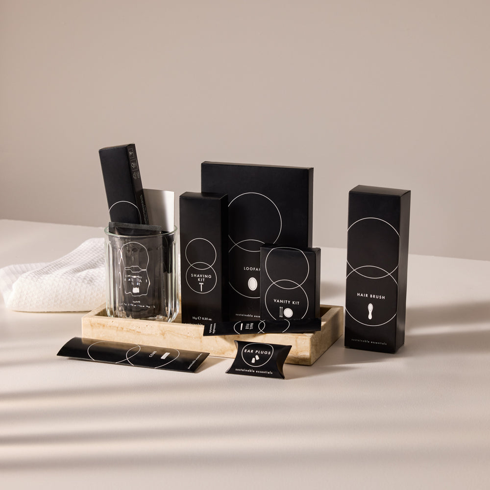 An assortment of sleek black hotel amenity kits neatly arranged in a marble vanity tray.