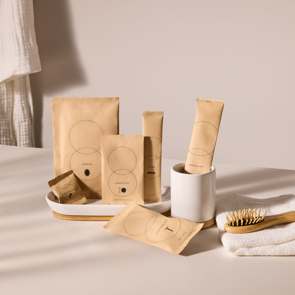 An assortment of brown paper hotel amenity kits arranged neatly in a white ceramic tray.